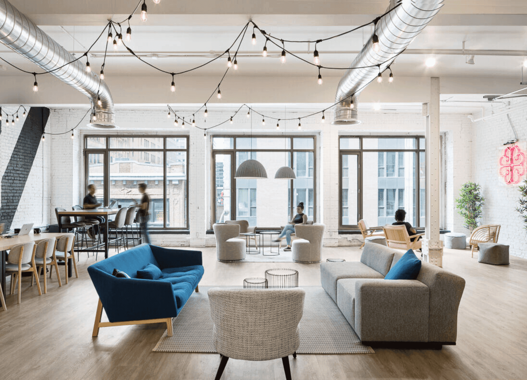 Office corridor with glass-walled meeting rooms and people working inside