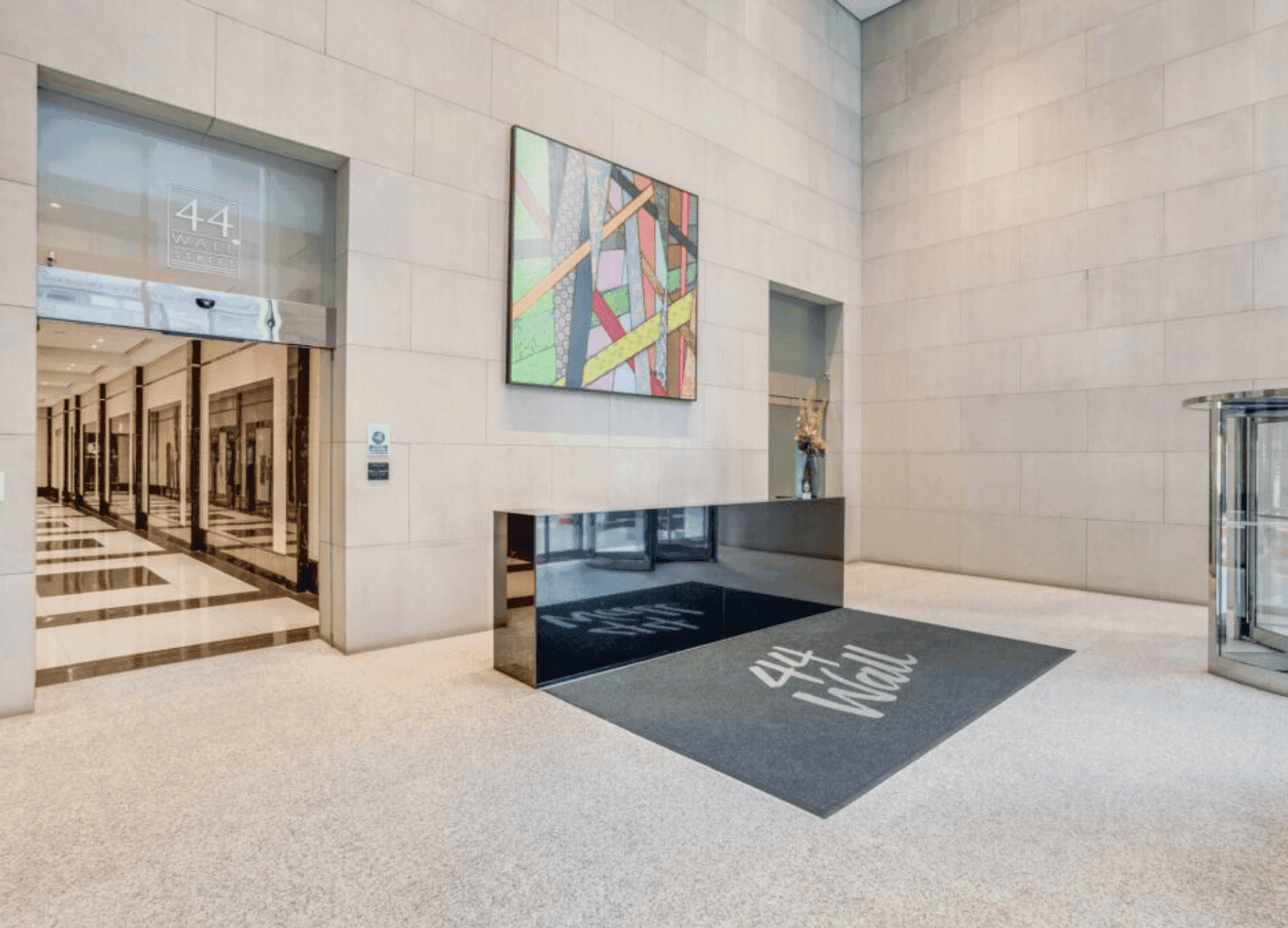 Elegant office reception area with a black desk, abstract artwork, and a long corridor