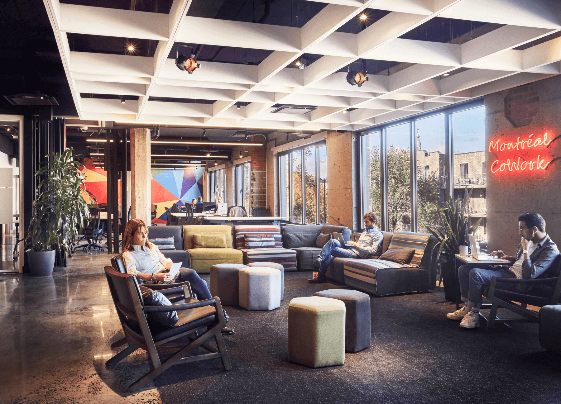 Modern coworking space with colorful furniture, plants, and people working on laptops