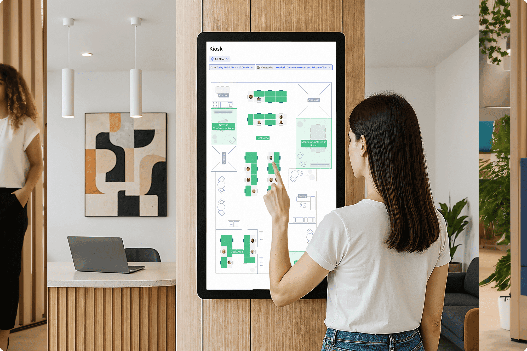 Woman interacting with a large touchscreen kiosk displaying an Archie floor plan for desk and room bookings in an office.