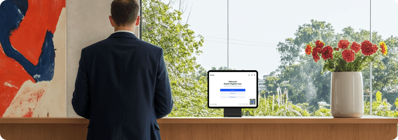 A person standing at a reception desk with a tablet displaying a guest registration screen.