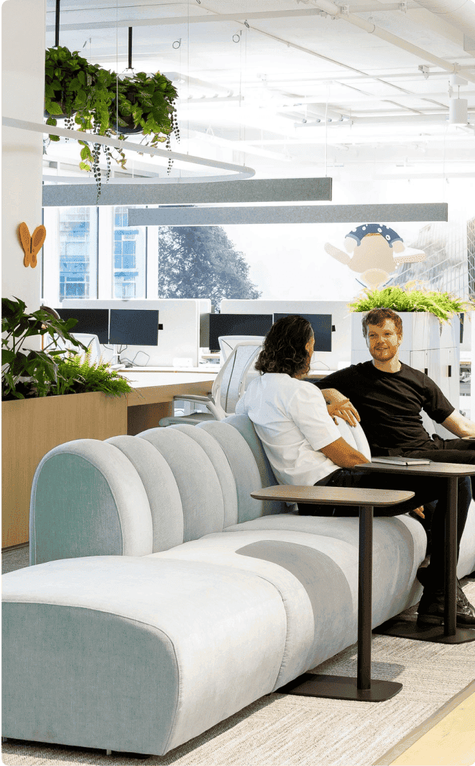 Two individuals working collaboratively in a modern office with laptops and notebooks