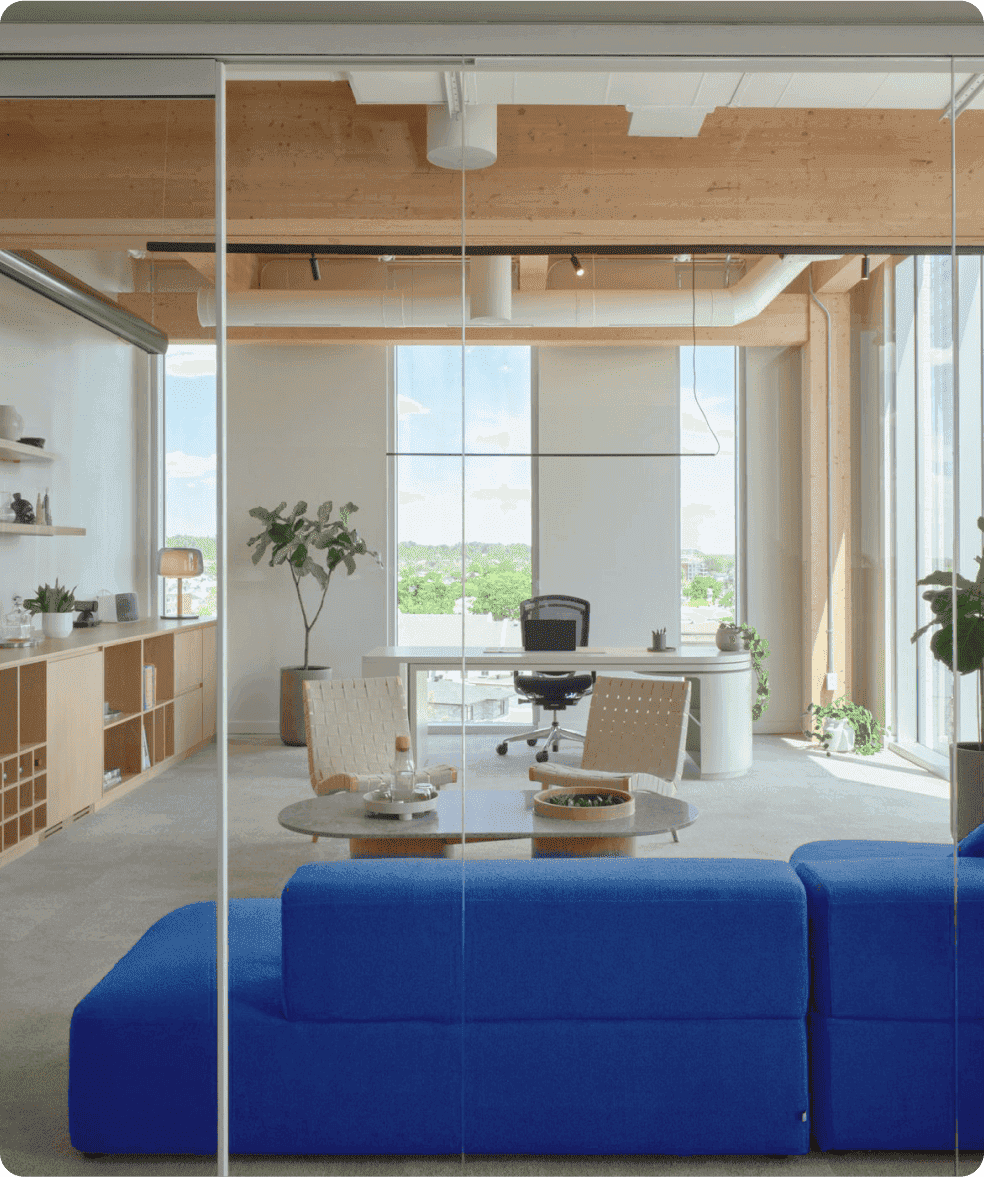 Modern office space with blue sofas, wooden shelves, and a view of the city.