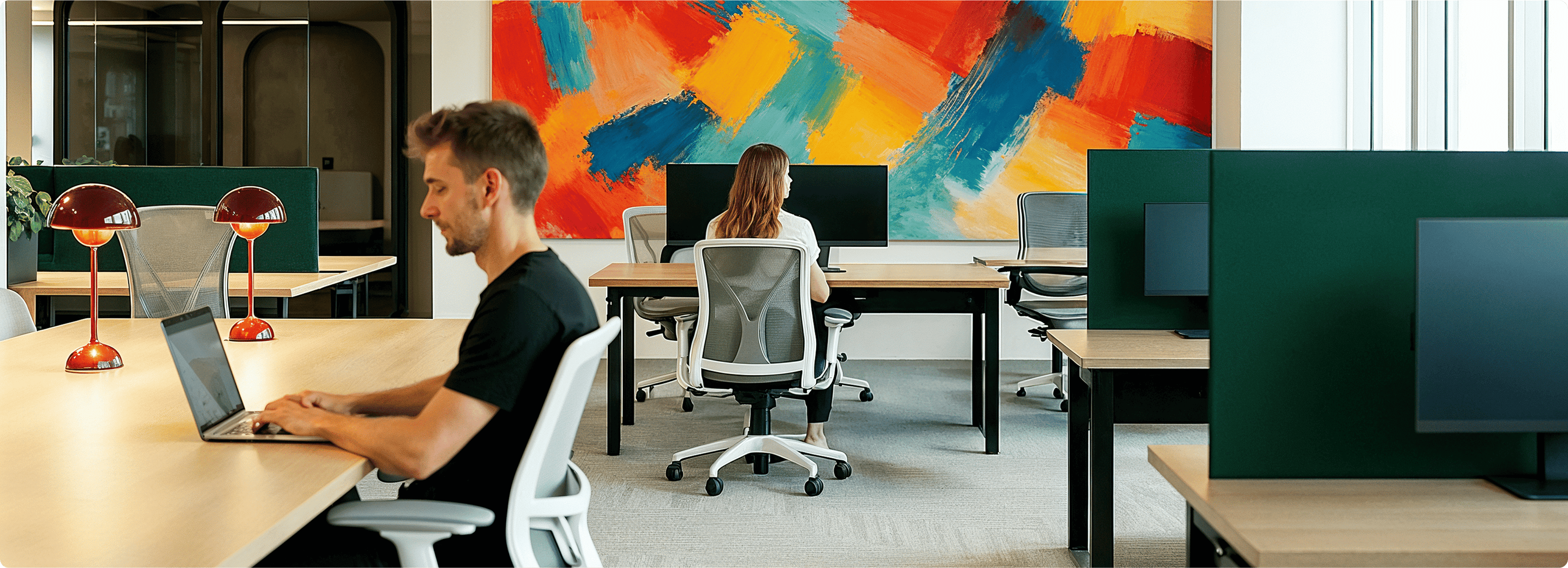 Modern office workspace with multiple desks, chairs, and a colorful abstract wall art.
